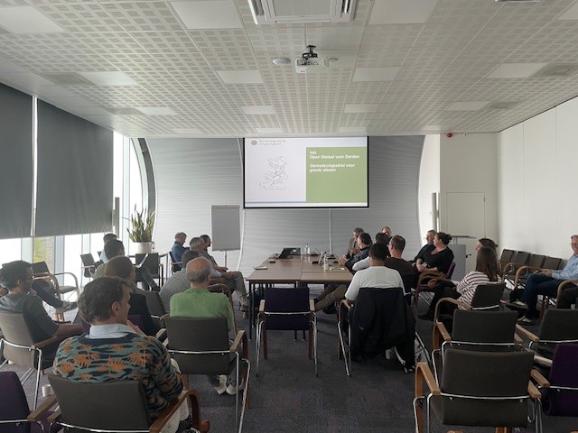 Zaal met mensen die kijken naar een presentatie.